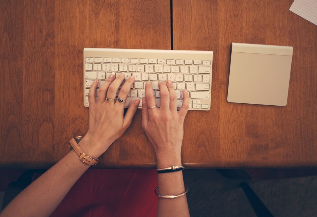 Hände tippen auf einer Tastatur auf einem Schreibtisch