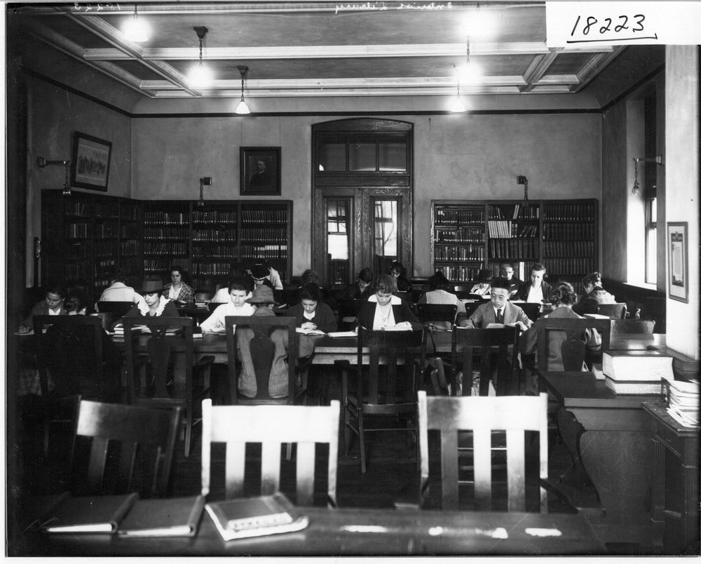 Schwarz-Weiß-Aufnahme eines historischen Lesesaals mit Bücherschränken und Studierenden